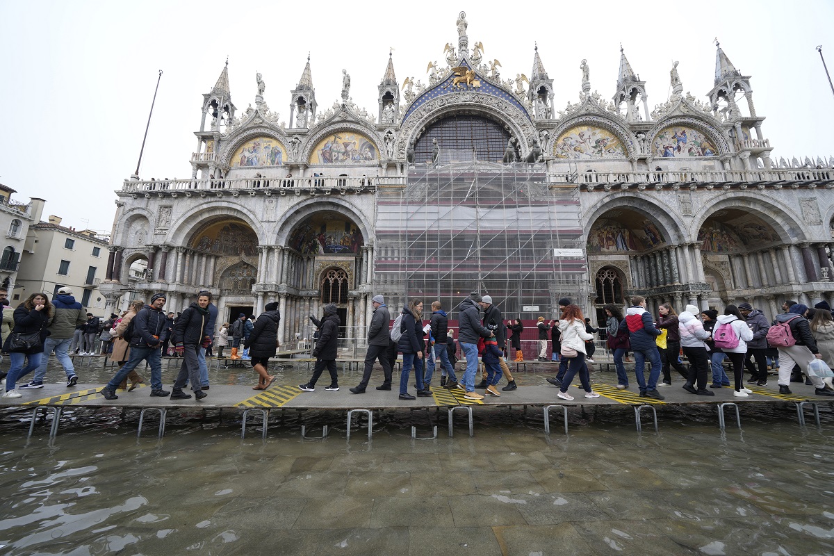 tourists and residents walk on catwalks in front of st. marks basilica in venice